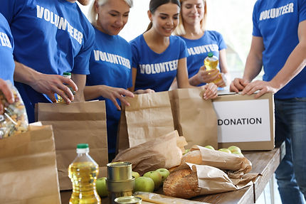 Team of volunteers collecting food donations at table, closeup.jpg
